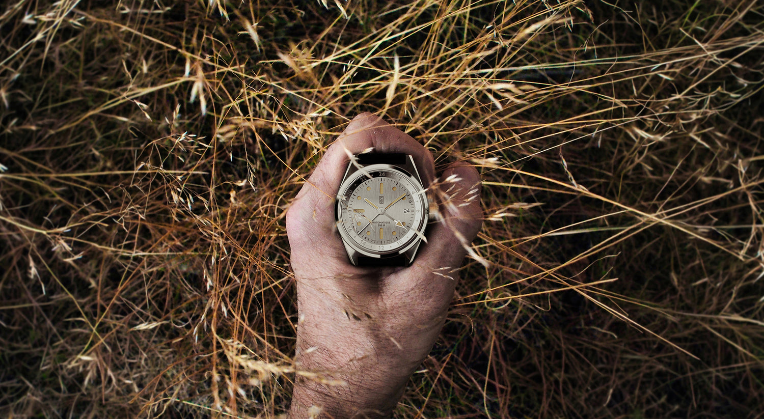 Swiss made cb01 GMT watch hold in hand above grass