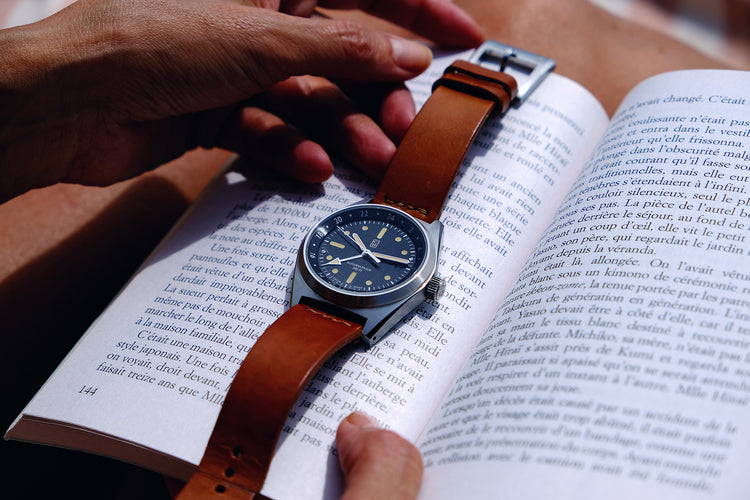 Men taking the Cedric Bellon CB01-GMT watch sitting on a book. Cosy ambiance
