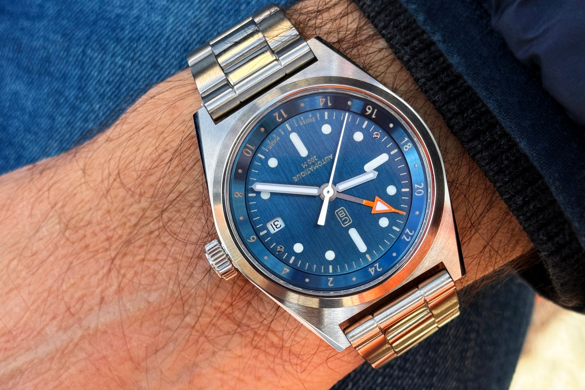 The denim blue dial of the full recycled steel watch Cedric Bellon CB01 GMT made in Swiss, worn by a men