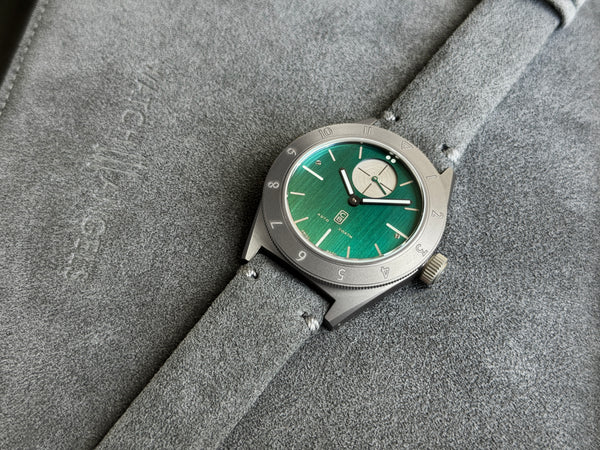 GMT automatic watch, with a deep green dial made of repurposed titanium for maximum sustainability, alcantara strap on alcantara pouch