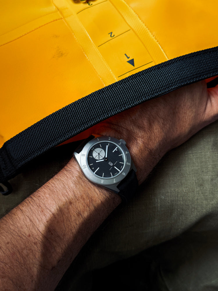 Tool watch made in Switzerland worn next to a yellow dive bag