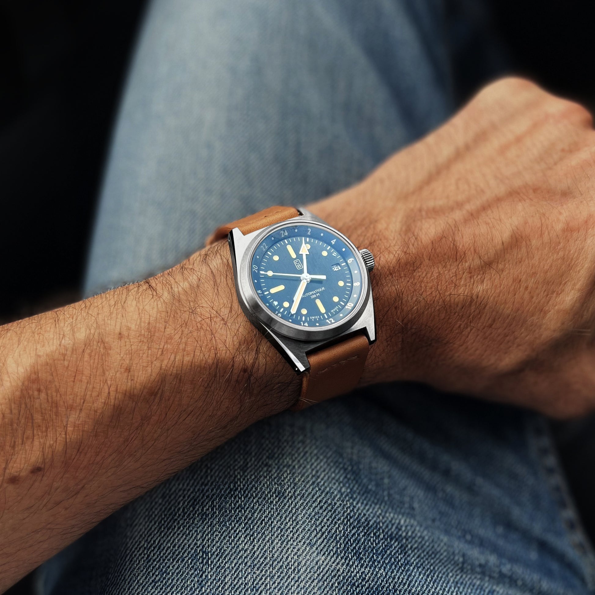 CB01-GMT 60 black dial watch worn by a men, denim as background