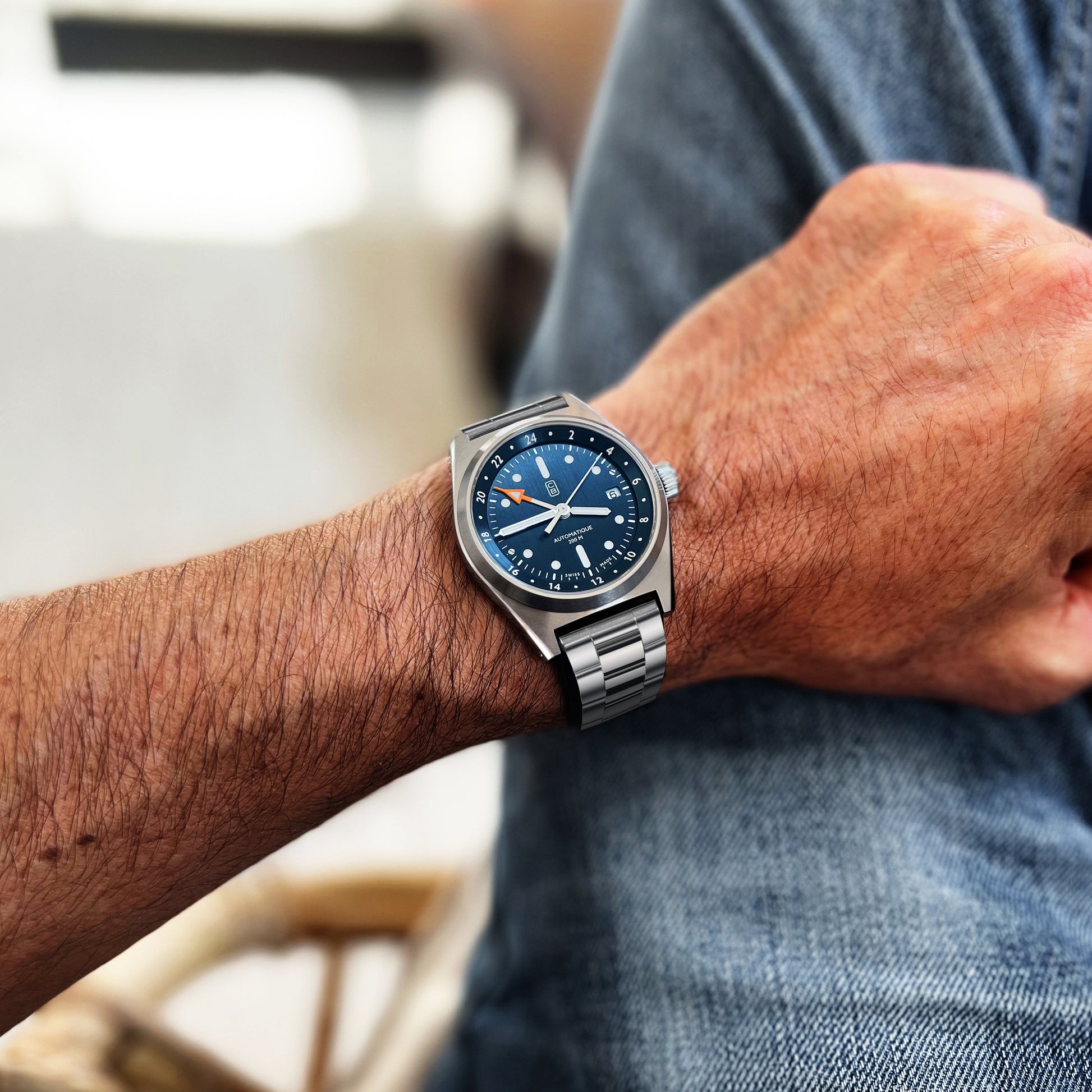 The Cedric Bellon CB01 GMT sustainable tool watch worn on men's wrist, denim as background.